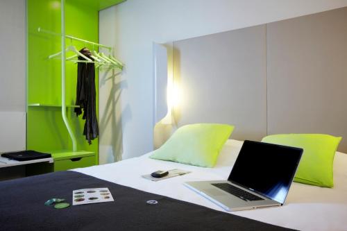 un ordinateur portable assis au-dessus d'un lit dans l'établissement Campanile Lyon Ouest Tassin, à Tassin-la-Demi-Lune
