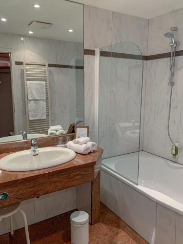 a bathroom with a sink and a tub and a shower at Hotel Zum Stein Wellness & Genuss Resort in Oranienbaum-Wörlitz