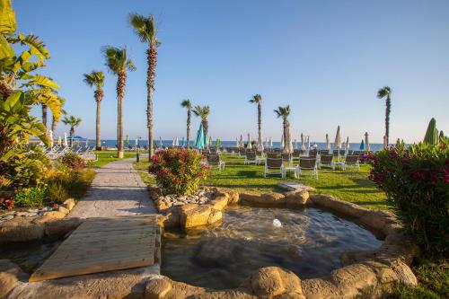 a garden with a pond and palm trees on the beach at Leonardo Cypria Bay in Paphos City