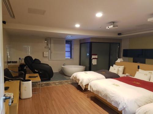 a hotel room with two beds and a bath tub at No.1 New Yorker Hotel in Jinju