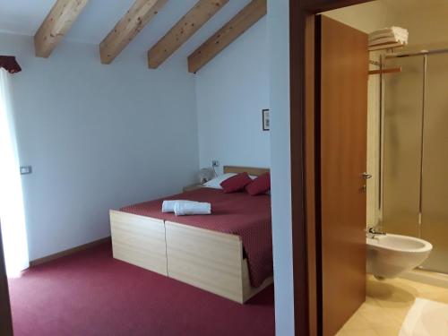 a bedroom with a bed and a bathroom with a toilet at Hotel Bellaria in Levico Terme