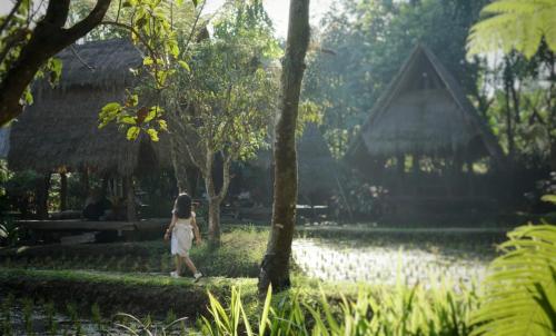 a young girl walking through a park with a building at Sapulidi Cafe, Gallery & Resort in Lembang