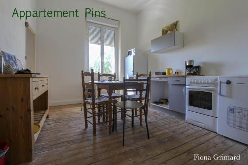 eine Küche mit einem Tisch und Stühlen im Zimmer in der Unterkunft BUREAUX Appartements LESPARRE MEDOC in Lesparre-Médoc