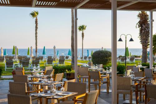 a patio with tables, chairs, tables and umbrellas at Leonardo Cypria Bay in Paphos