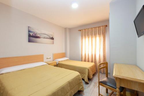 Habitación de hotel con 2 camas y escritorio en Olympia Ronda Hostel en El Puig