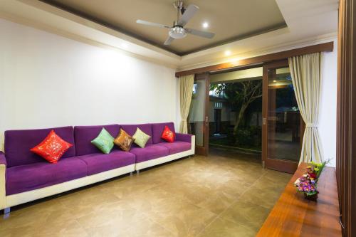 a living room with a purple couch with colorful pillows at Villa Sabasanti Gianyar in Keramas