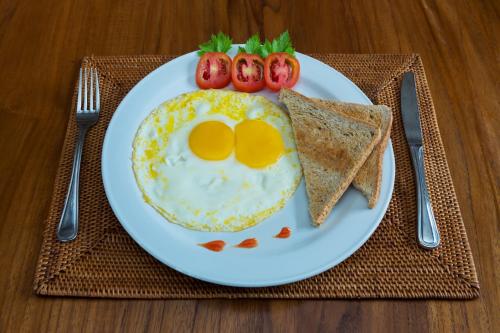 a plate of breakfast food with eggs and toast and strawberries at Villa Sabasanti Gianyar in Keramas