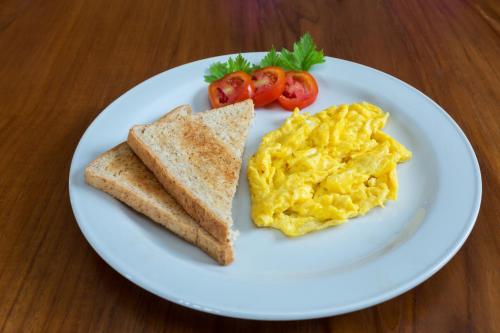a white plate with scrambled eggs and toast and tomatoes at Villa Sabasanti Gianyar in Keramas