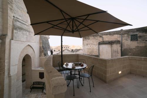 una mesa y sillas con una sombrilla en el balcón en Albergo Del Sedile en Matera