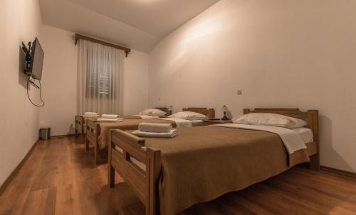 a bedroom with three beds and a tv and a window at Hotel Park Drniš in Drniš