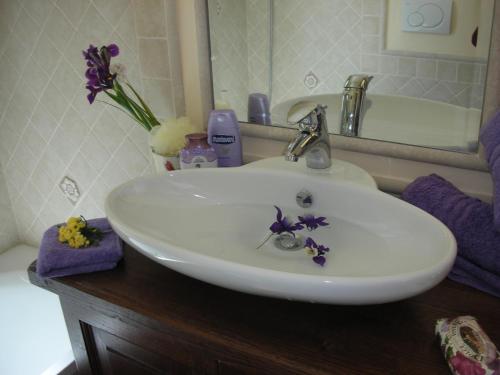 un lavabo blanco con flores púrpuras. en B&B Casacapraia, en Itri