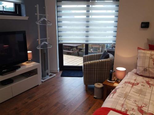 a bedroom with a bed and a tv and a window at Byers Guest house in Banavie