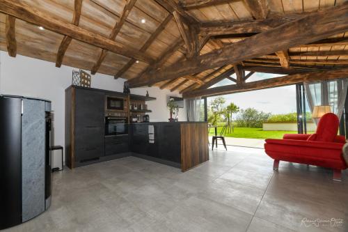 Il comprend un salon avec une chaise rouge et une cuisine. dans l'établissement Gites De La Grande Borderie, à Saint-Gervais