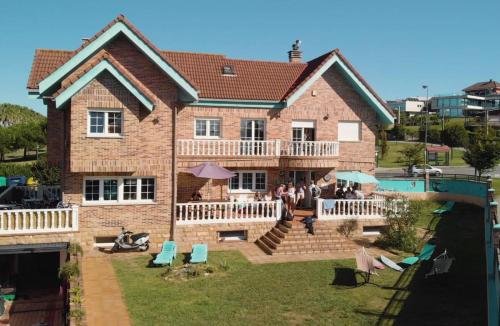 a large brick house with people sitting on the patio at Gijon Surf Hostel in Gijón