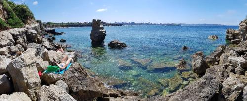 a group of people sitting on rocks in the water at Gijon Surf Hostel in Gijón