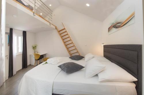 a white bedroom with a large white bed with pillows at Central Old Town Rooms in Split