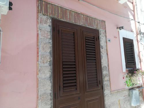 una puerta de madera en el lateral de un edificio rosa en Terra e Mare, en Capaci