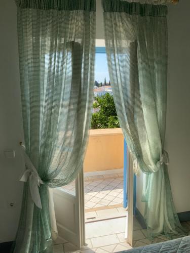 a bedroom with green curtains and a window at Palio Limani (Old Harbour) in Spetses