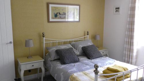 ein Schlafzimmer mit einem Bett mit zwei Nachttischen und zwei Lampen in der Unterkunft The Lodge Greatwood in Ipswich