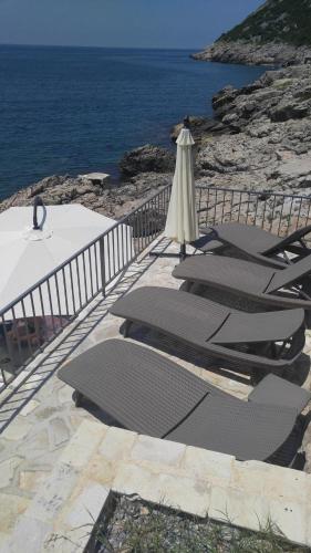 a row of chairs with an umbrella and the ocean at Your Home Montenegro in Dobra Voda
