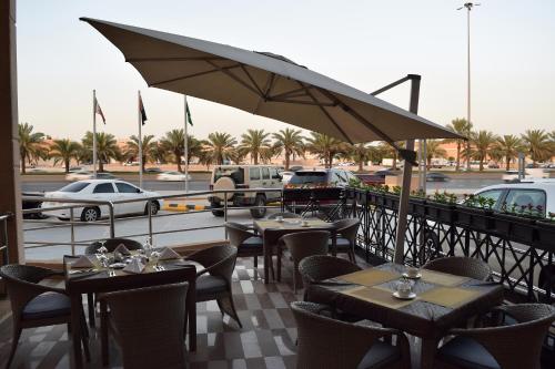 a restaurant with tables and chairs and a parking lot at Best Plus Aurora Hotel in Riyadh