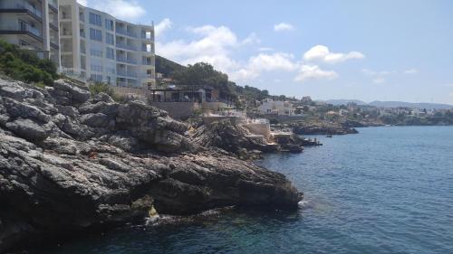 a building on a cliff next to the water at Your Home Montenegro in Dobra Voda