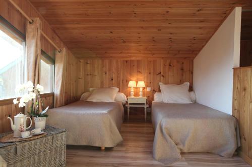 two beds in a room with wooden walls and wooden floors at Chambres "Au Jardin" in Biscarrosse