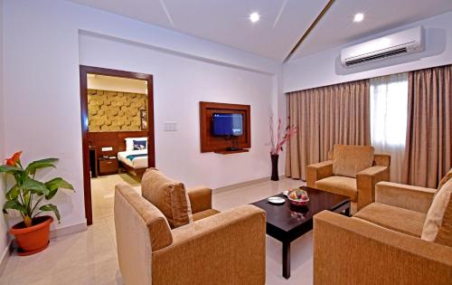 a living room with a couch and chairs and a television at I V Sanctum Hotel in Bengaluru