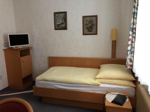a small bedroom with a bed and a television at Gasthof Koller in Mariasdorf