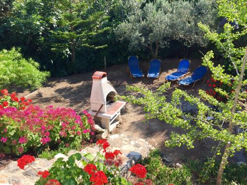 three chairs and a bench in a garden with flowers at Carpe Diem in Zipárion