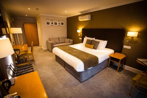 a hotel room with a large bed and a chair at Heywood Spa Hotel in Tenby