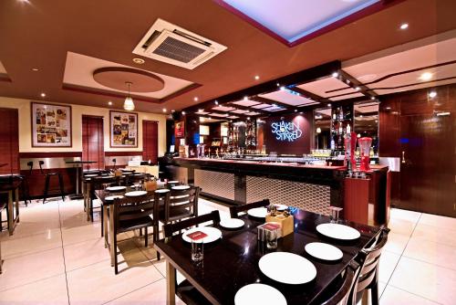 a restaurant with tables and chairs and a bar at I V Sanctum Hotel in Bengaluru