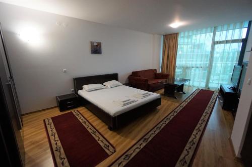 a bedroom with a bed and a chair and a television at Apartments in hotel Primorsko Del Sol in Primorsko