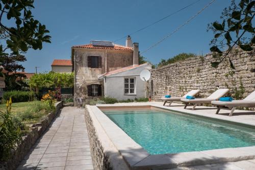 einen Pool vor einer Steinmauer mit zwei Stühlen und einem Haus in der Unterkunft Unique Antistress Oasis Villa Antiqua in Osor