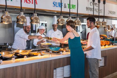 a group of people standing in a kitchen preparing food at Leonardo Plaza Cypria Maris Beach Hotel & Spa in Paphos City