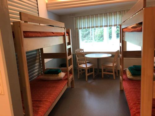 ein Zimmer mit Etagenbetten, einem Tisch und einem Tisch in der Unterkunft Luontoleirikeskus Lankari in Seinäjoki