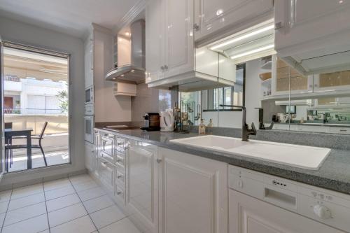 une cuisine avec un évier et une grande fenêtre dans l'établissement Appartement Palais Milton, à Cannes