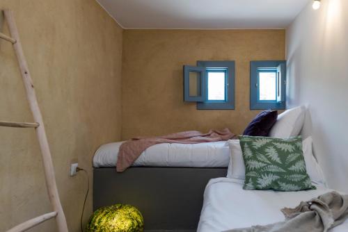 a bedroom with a bed and a ladder and two windows at La Maison des Sources in ‘Ayn Zḩaltā