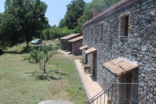 a stone building with a bench on the side of it at Agriturismo La Caraffara sull' Etna in Puntalazzo