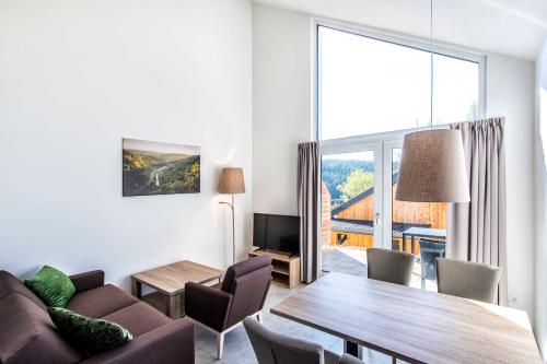 a living room with a table and a large window at Panoramabungalow _DH_ im Feriendor in Truppach