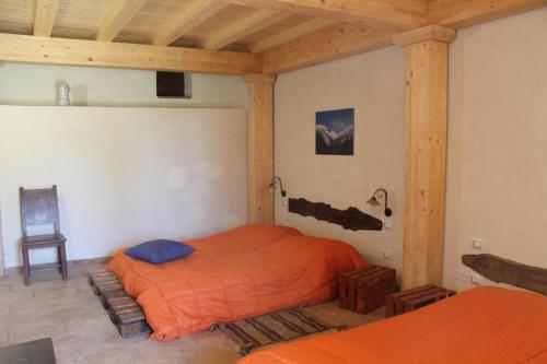 a bedroom with a bed with an orange comforter at Agriturismo La Caraffara sull' Etna in Puntalazzo