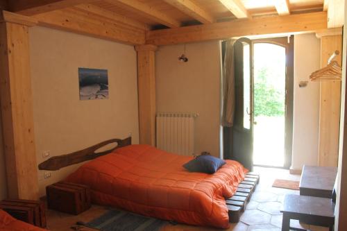 a bedroom with a bed with an orange blanket at Agriturismo La Caraffara sull' Etna in Puntalazzo