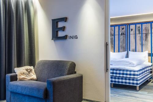 a room with a chair and a bed with a letter e at Adler Suite & Stube in Villabassa