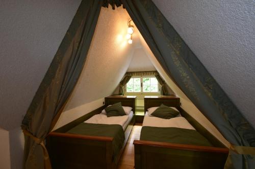 two beds in a attic room with a window at Sant Georg Garni in Mariánské Lázně