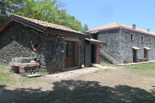 a stone house with a door and a building at Agriturismo La Caraffara sull' Etna in Puntalazzo
