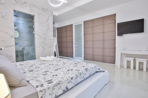 a white bedroom with a large bed and a tv at Hotel Paradise Road in Kutaisi