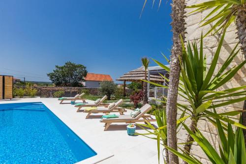 a villa with a swimming pool and lounge chairs at Vila Gallo in Galovac
