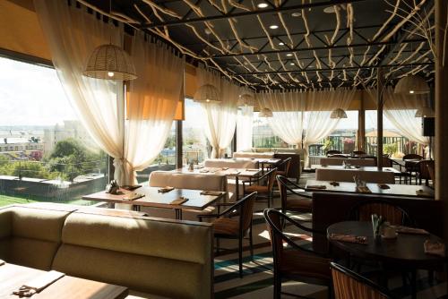 カザンにあるHotel Imeretiのテーブルと椅子、大きな窓のあるレストラン