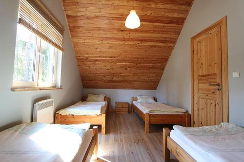 a room with two beds and a wooden ceiling at domki letniskowe Gnieźnieńska Pobierowo in Pobierowo