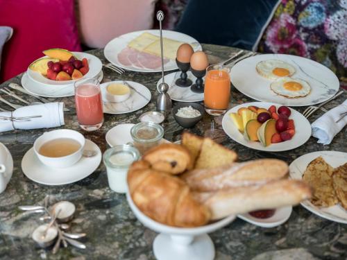 a table topped with plates of breakfast foods and drinks at Yndo Hôtel in Bordeaux